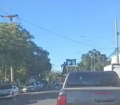 Mueven maquinaria pesada por Alem y un trabajador levanta los cables con una rama